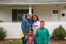 A family poses in front of their ICCF community land trust home.