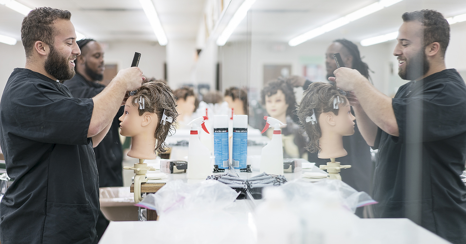 Flint, MI - Tuesday, February 6, 2018: Junior barbers Cole Stomp, 19, from Davison, and Tony Atlas, 32, from Flint practice on mannequins at the Flint Institute of Barbering.