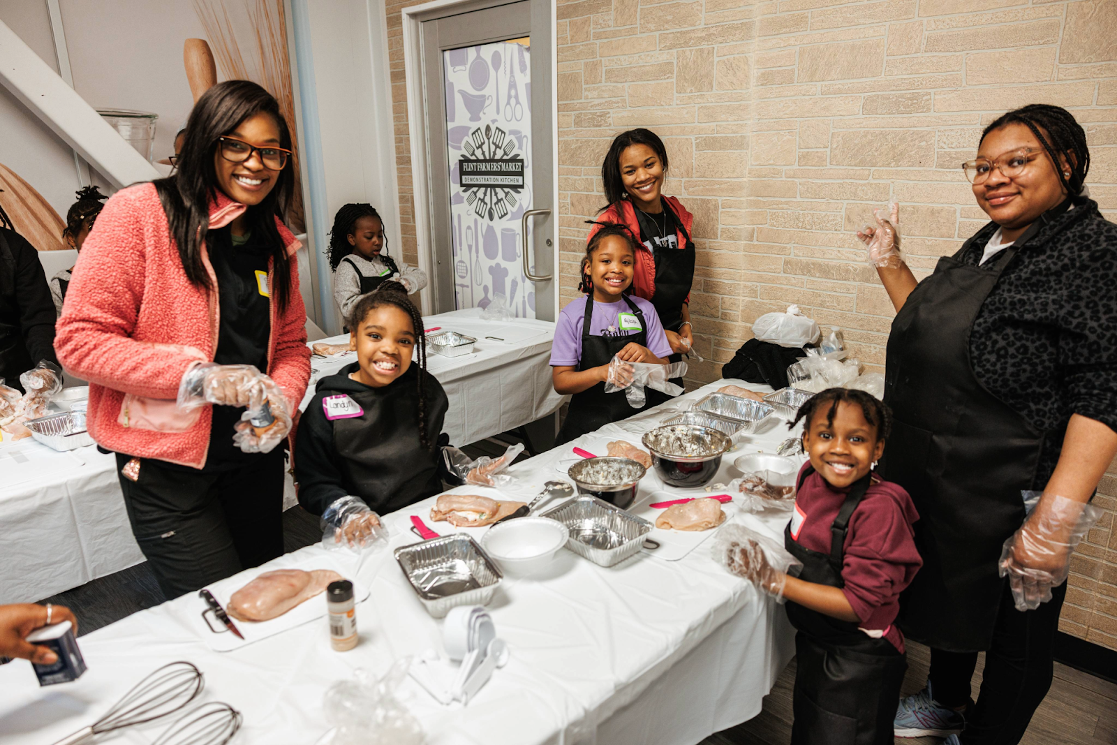 Mothers and daughters pose during Mission Possible's NourisHER class at the Flint Farmers' Market on May 11, 2024.